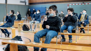 Schulkinder machen Corona-Schnelltests in der Sporthalle ihrer  Schule.