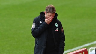 Werder-Trainer Florian Kohfeldt hält sich frustriert die Hand vors Gesicht.