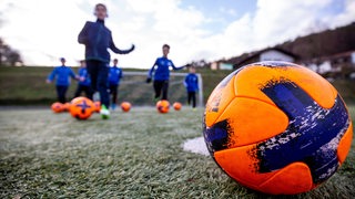 Mehrere Kinder rennen beim Fußball-Training auf einen Ball zu. 