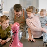 Vater mit drei Kindern an einer Küchenmaschine