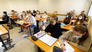 Schüler einer weiterführenden Schule sitzen mit Maske im Unterricht.
