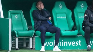 Werder-Trainer Florian Kohfeldt sitzt auf der Bank und ärgert sich. (Archivbild)