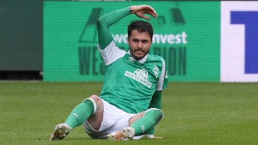 Leonardo Bittencourt sitzt auf dem Boden des Weser-Stadions und wedelt mit dem rechten Arm.