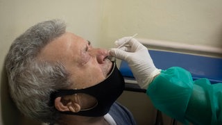 Ein Mann bekommt ein Corona-Teststäbchen in die Nase eingeführt