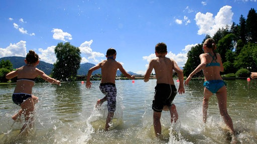 Vier Kinder laufen in einen See