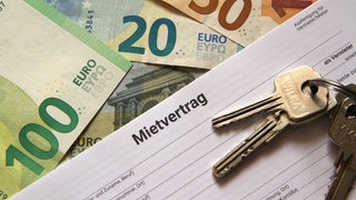 Ein Mietvertrag liegt auf Bargeld.