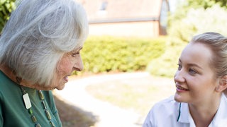 Eine junge Altenpflegerin unterhält sich mit einer Seniorin