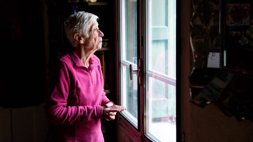 Eine alte Frau blickt verloren aus einem Fenster