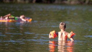 Ein Kind mit Schwimmflügeln geht in einen See