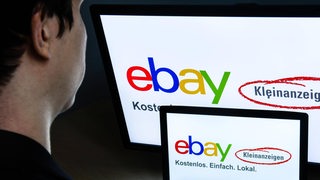 Ein Mann schaut auf Bildschirme, auf denen das Ebay-Kleinanzeigenlogo zu sehen ist (Symbolbild)