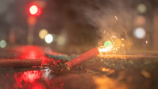 Ein Böller wird bei Nacht auf einer Straße gezündet (Symbolbild)