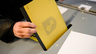 Wahlzettel mit Bremer Schlüssel wird in eine Urne gesteckt (Archivbild)