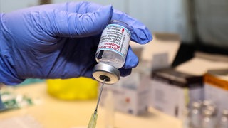 Eine Spritze wird mit Moderna Impfstoff aufgezogen.