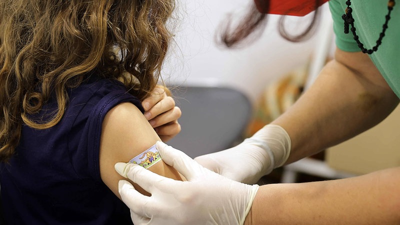 Ein Kind bekommt nach einer Impfung ein Pflaster auf den Oberarm.