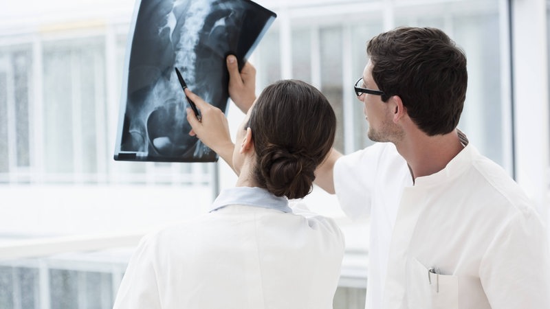 Eine Ärztin und ein Arzt begutachten ein Röntgenbild.