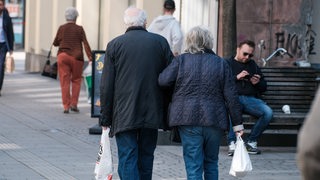 Zwei Menschen laufen durch eine Fußgängerzone.
