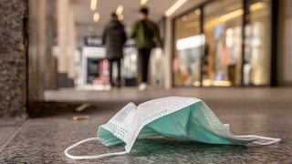 Weggeworfener Mundschutz liegt in einer Fußgängerzone auf dem Boden (Symbolbild)