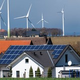 Wohnhäuser mit Solaranlagen im Hintergrund Windkrafträder