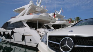Symbolfoto: Vor einer Luxusyacht steht ein teurer Mercedes