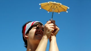Frau mit einem Mini-Sonnenschirm zum Schutz vor der Sonne.