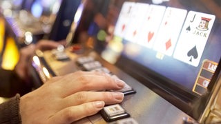 Eine Frau bedient spielt an einem Glücksspielautomaten (Archivbild)