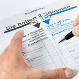 Nahaufnahme eines Stimmzettels zur Bundestagswahl, über dem eine Hand mit einem Stift ruht.