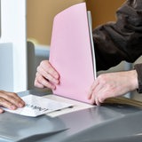 Stimmzettelumschlag wird in eine Wahlurne gesteckt