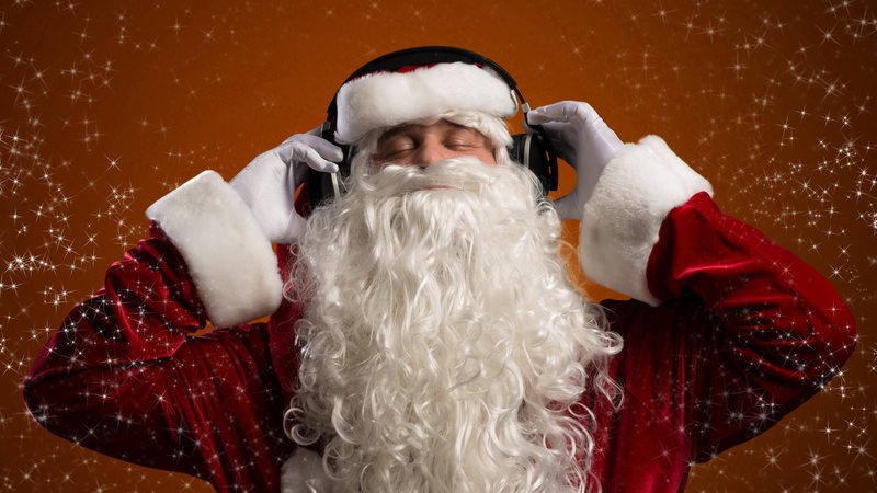Ein Weihnachtsmann hört Musik über Kopfhörer.