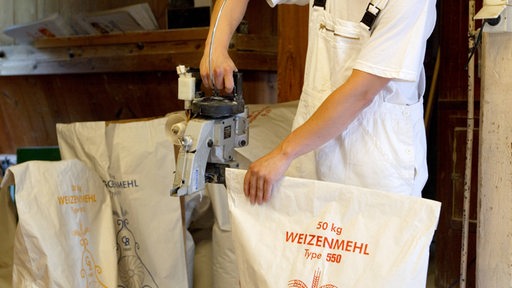 Ein Müller verschließt einen abgefüllten Weizenmehlsack (Archivbild)