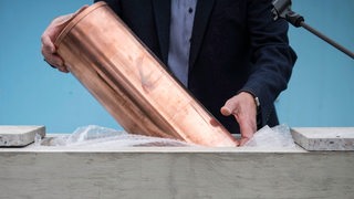 Ein Mann legt eine Zeitkapsel in ein Fundament (Symbolbild)