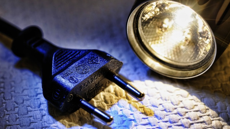 Stecker und Taschenlampe als Symbol für Stromausfall