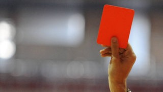 Ein Schiedsrichter hält eine rote Karte hoch.