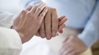 Hände halten die Hand eines Patienten