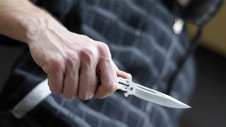 Mann hält ein verbotenes Messer in der Hand (Symboldbild).