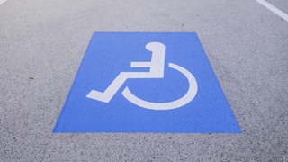 Ein Rollstuhlsymbol auf dem Asphalt einer Straße