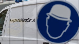 Fahrzeug eines Kampfmittelräumdienstes hinter einem Zaum mit Schild (Symbolbild)