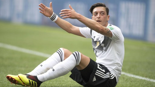 Mesut Özil gestikuliert am Boden sitzend während eines WM-Spiels.