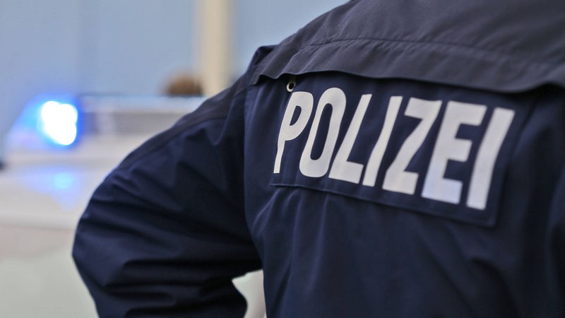 Rücken eines Polizisten, mit dem Schriftzug Polizei.