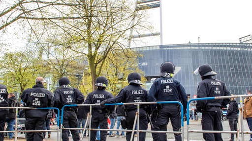 Mehrere Polizeibeamte mit Helmen stehen vor Absperrungen am Weserstadion.