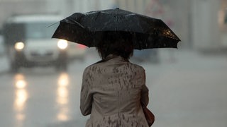 Starkregen: eine Person durchnässt unter einem Regenschirm