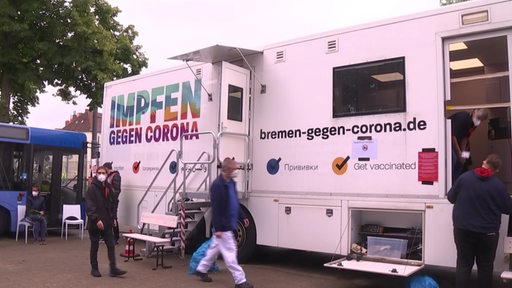Impfbereite Menschen stehen an einem Impfbus in Bremen.