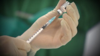 Eine Impfdosis wird vorbereitet und aus einer Ampulle in die Spritze gezogen.
