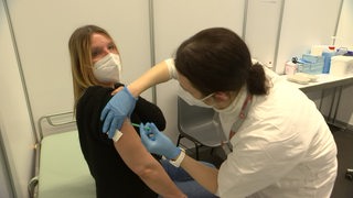 Eine Frau bekommt eine Impf-Spritze in den Oberarm.