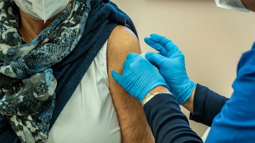 Eine Frau bekommt nach ihrer Impfung ein Pflaster auf ihren Oberarm geklebt.