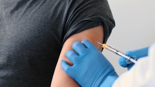 In einen Oberarm wird eine Impfung mit einer Spritze gegeben. 