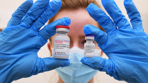 Eine Ärztin mit Maske hält die Impfstoffe von Moderna und Biontech/Pfizer in die Kamera