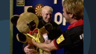 Ein großer Stoff-Teddy wird 1985 dem Sieger des Darts-Turnier am Rande des Bremer Freimarkts überreicht.