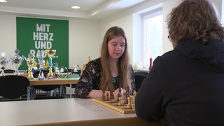 Werders Schach-Talent Lara Schulze sitzt vor einem Brett und ihrem Gegner.