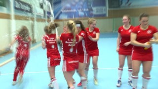 Spielerinnen des Bremer HC feiern mit einer Sektdusche in der Halle den Aufstieg.