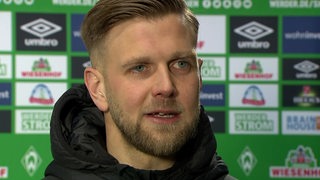 Werder-Stürmer Niclas Füllkrug nach dem Spiel vor einer Werbewand im Interview.